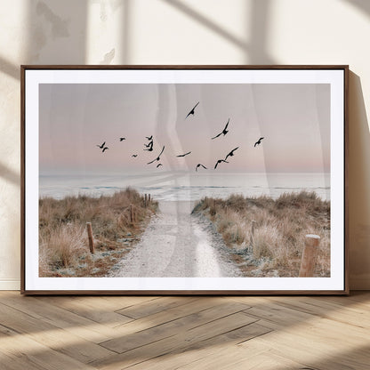 A peaceful coastal pathway leading to the ocean, with birds flying across a soft pastel sky, creating a calm and scenic beach atmosphere.