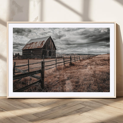 Framed canvas of a rustic barn under a moody sky with weathered fence and dark fields, ideal for farmhouse or rural-style wall decor.