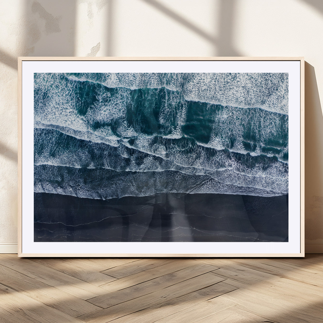 Canvas of aerial ocean waves crashing onto a black sand beach in moody tones, ideal for modern coastal or minimalist home decor.