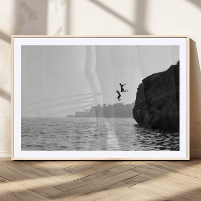 Black and white canvas of two figures cliff jumping into the sea, captured with moody tones, ideal for modern coastal or adventure-themed home decor.   2/2