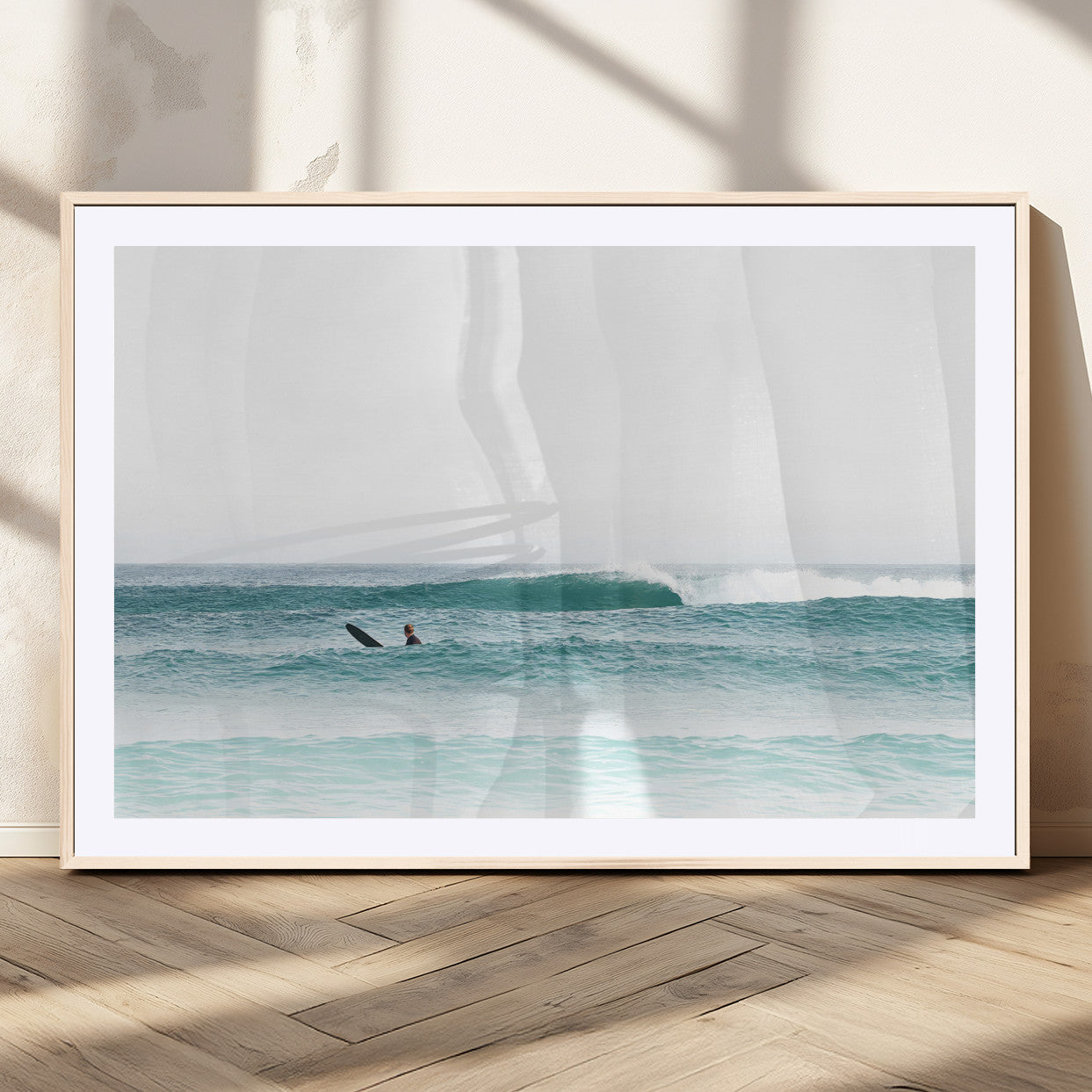 Minimalist photo of a lone surfer on calm aqua waves under bright sky, perfect for Scandinavian coastal or serene ocean-inspired home decor.
