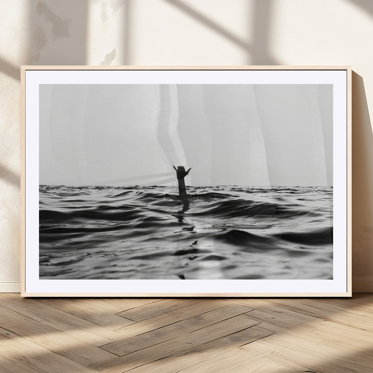 Black and white ocean with a hand making a surfer sign among dark waves, creating a dramatic and minimalist seascape with bold contrast.