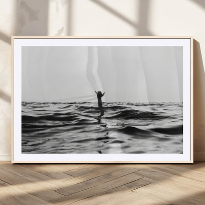 Black and white ocean with a hand making a surfer sign among dark waves, creating a dramatic and minimalist seascape with bold contrast.