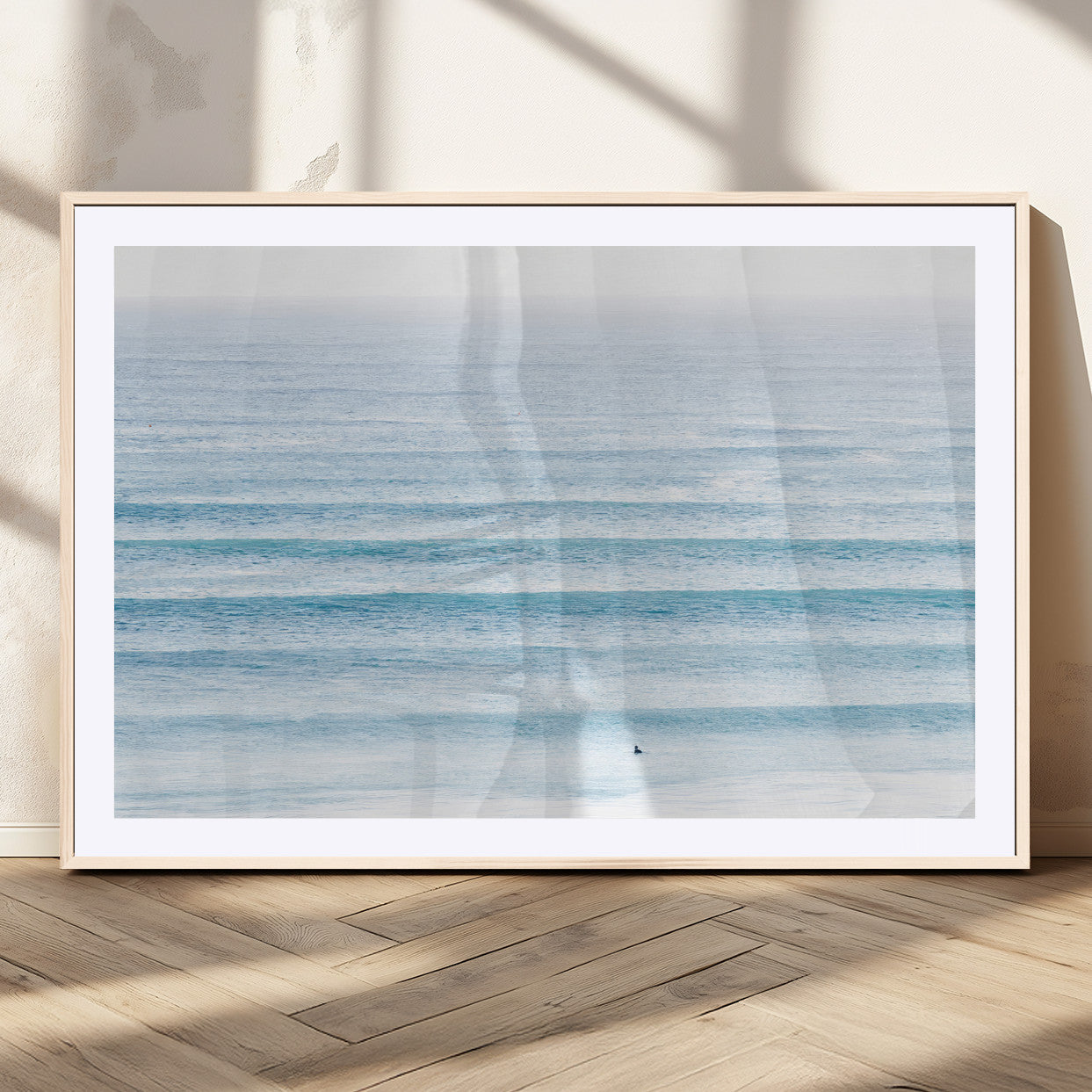 Minimalist ocean view with soft blue waves and a lone surfer, creating a serene and airy coastal aesthetic, perfect for tranquil home decor.