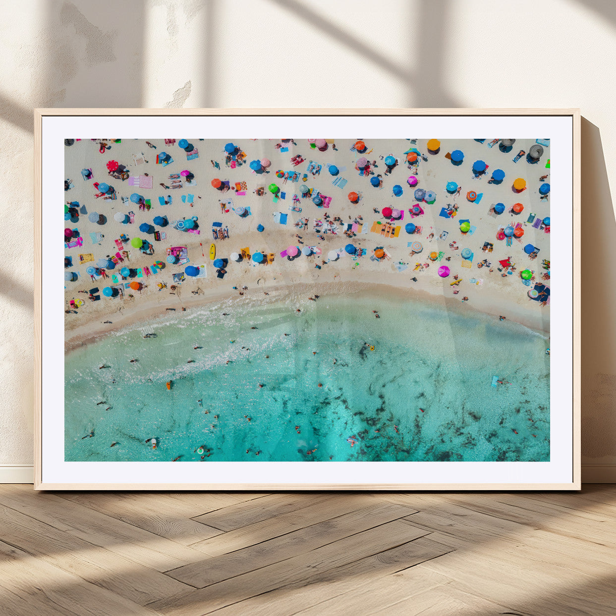 Aerial view of a vibrant beach filled with colorful umbrellas and people enjoying the turquoise ocean, capturing a lively summer vacation scene.