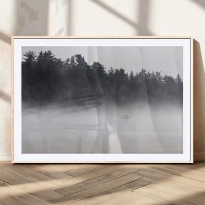 A lone surfer carrying a board through a misty shoreline, surrounded by dense trees and fog, creating a peaceful and mysterious coastal scene.