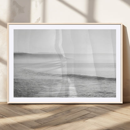 A black and white minimalist seascape featuring soft rolling waves and misty distant cliffs, creating a serene and timeless coastal atmosphere.