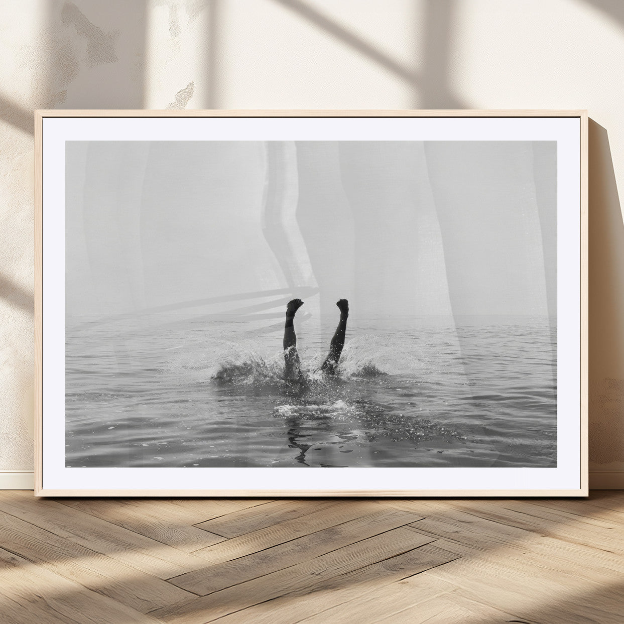 A black and white minimalist water scene capturing a playful splash as a swimmer dives upside down, creating a carefree and artistic aquatic aesthetic.