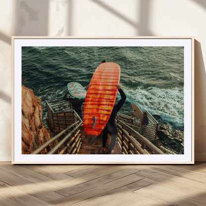 A surfer carrying a bold orange surfboard down a rugged staircase toward the ocean, bathed in golden hour light, capturing the energy of coastal adventure.