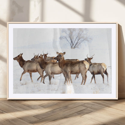 A group of elk standing on snowy terrain with a tree in the background, perfect for rustic or lodge-style winter wall decor.