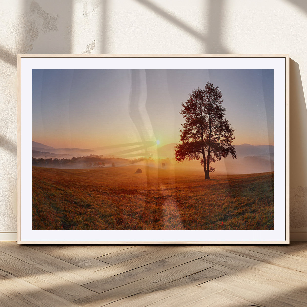 A tranquil landscape at sunrise with a mist-covered field and a lone tree, creating a peaceful and natural atmosphere.