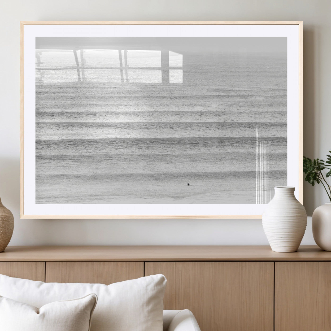 Monochrome photo of a lone surfer in calm layered waves, perfect for minimalist coastal or moody ocean-inspired wall decoration.
