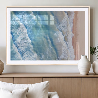 Aerial photo of soft blue waves meeting sandy shore, perfect for modern coastal or beach-themed decor with a light and tranquil aesthetic.