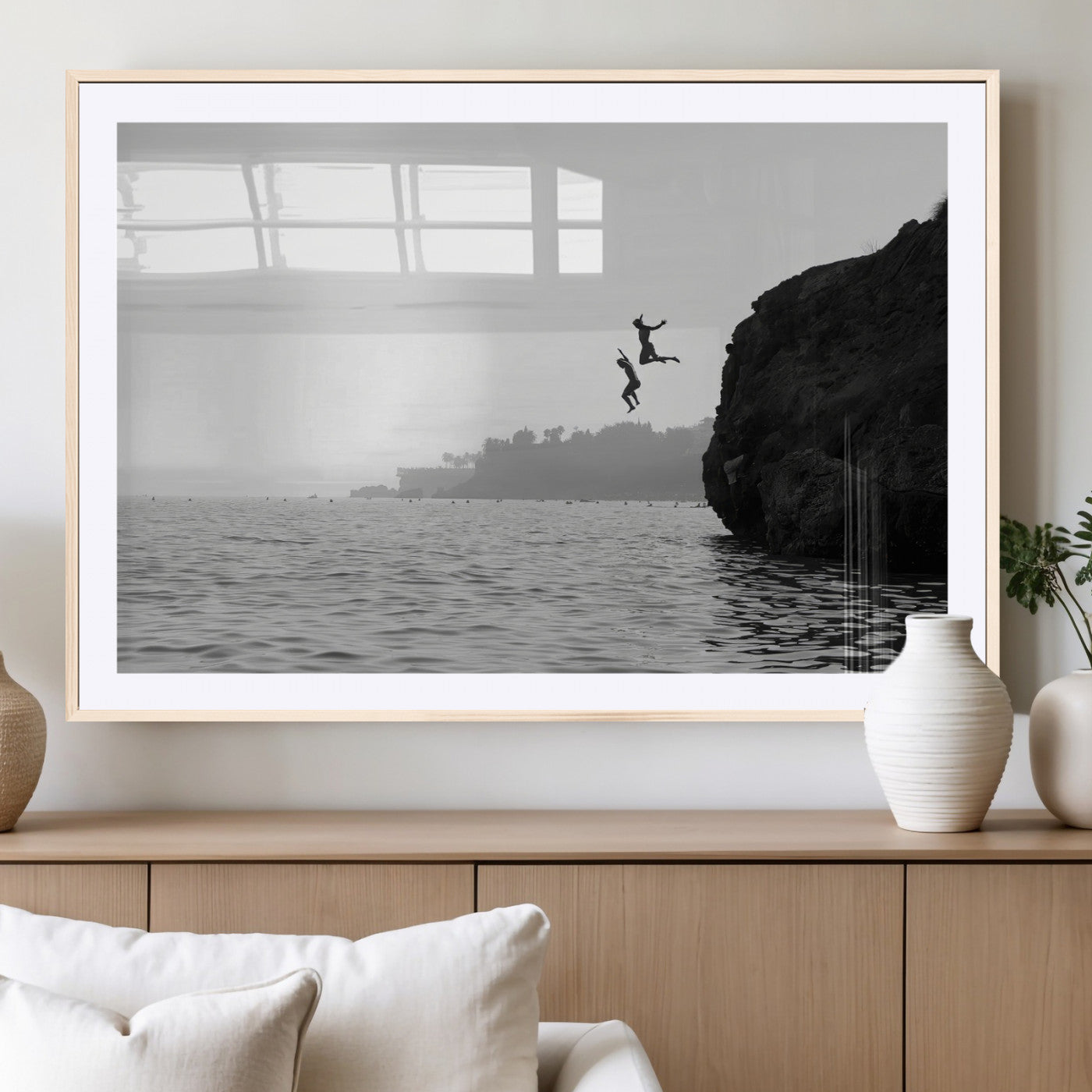 Black and white canvas of two figures cliff jumping into the sea, captured with moody tones, ideal for modern coastal or adventure-themed home decor.   2/2