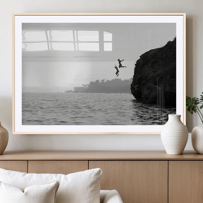 Black and white canvas of two figures cliff jumping into the sea, captured with moody tones, ideal for modern coastal or adventure-themed home decor.   2/2