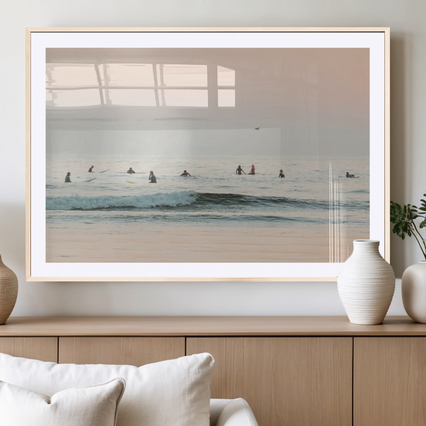 Dreamy photo of surfers waiting on soft pastel waves under a pink sunset sky, ideal for soft coastal minimalist or serene ocean-themed home decor.