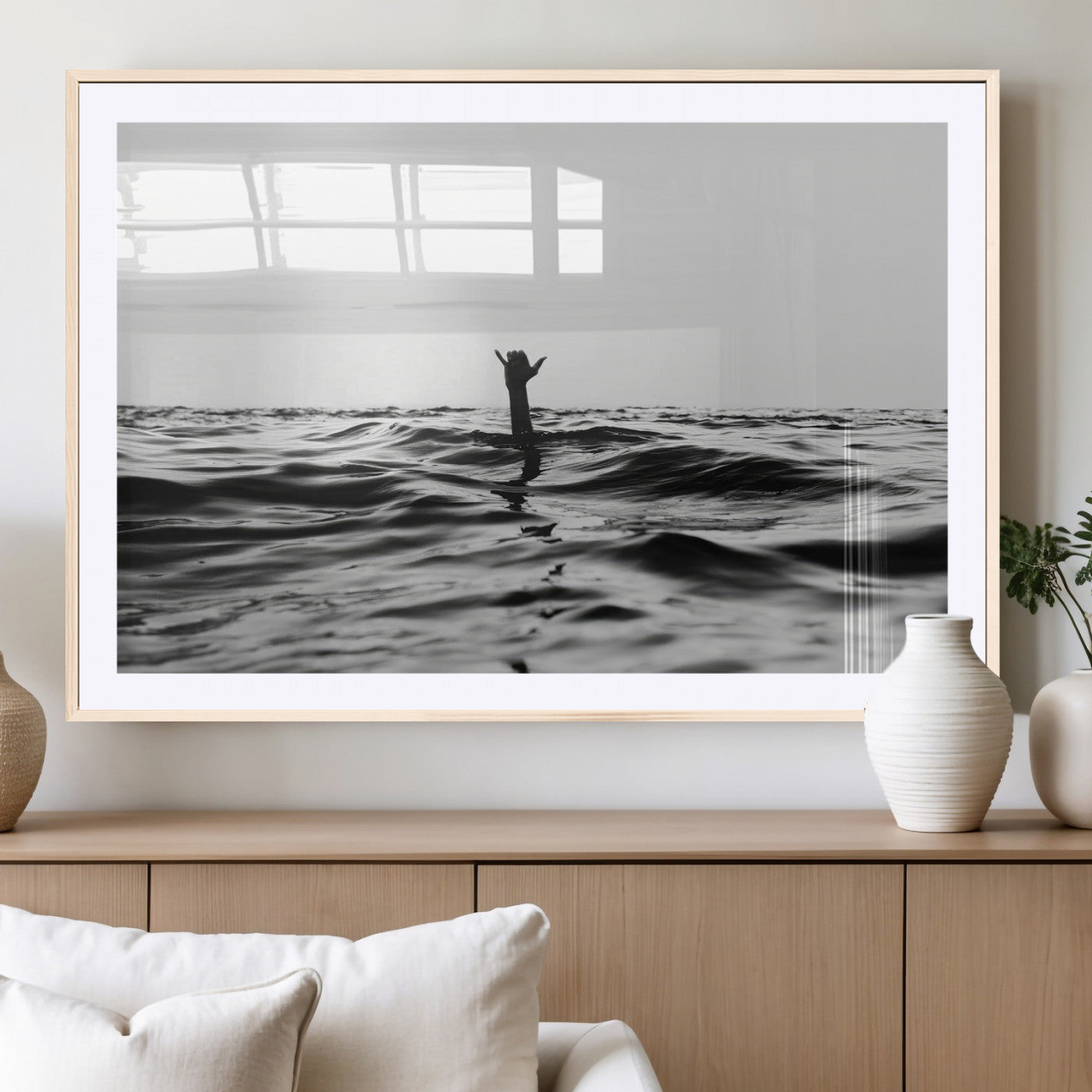 Black and white ocean with a hand making a surfer sign among dark waves, creating a dramatic and minimalist seascape with bold contrast.