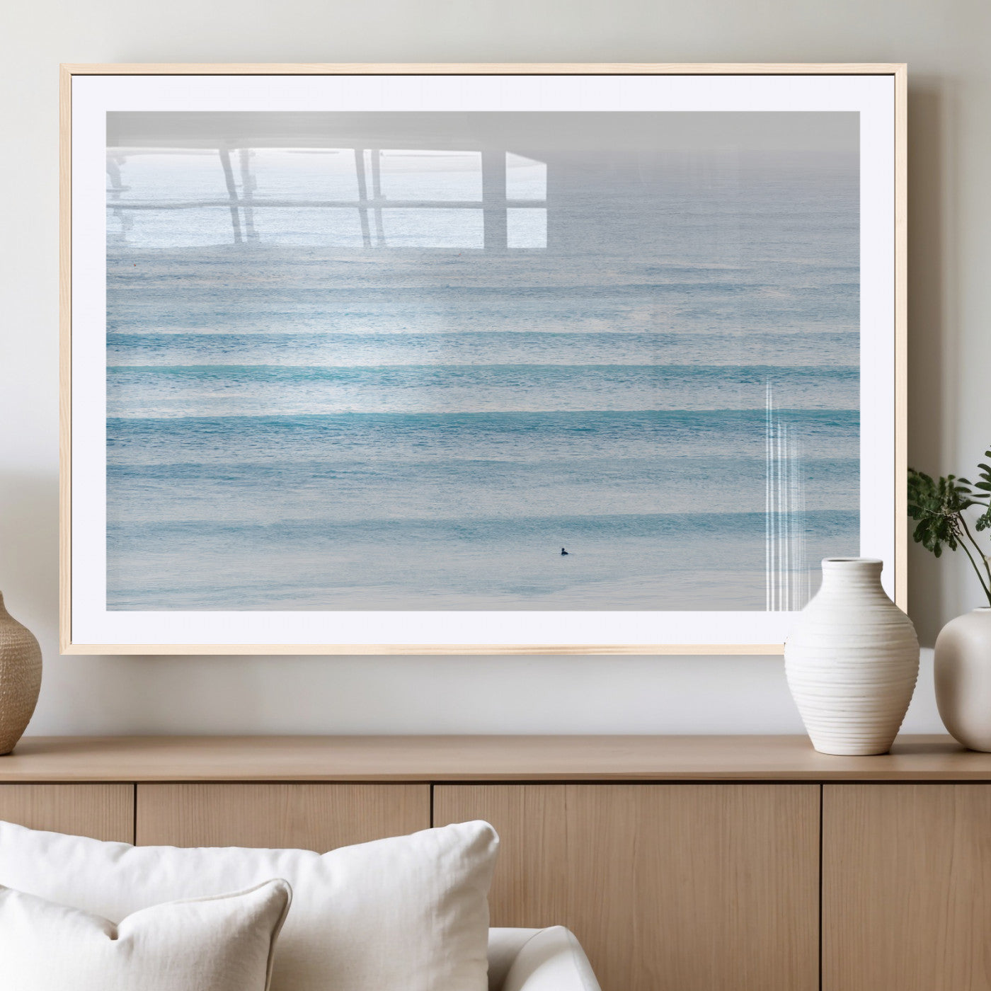 Minimalist ocean view with soft blue waves and a lone surfer, creating a serene and airy coastal aesthetic, perfect for tranquil home decor.