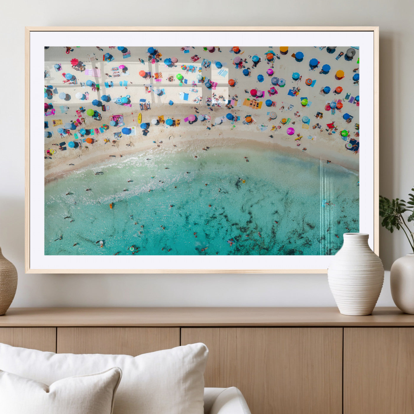 Aerial view of a vibrant beach filled with colorful umbrellas and people enjoying the turquoise ocean, capturing a lively summer vacation scene.