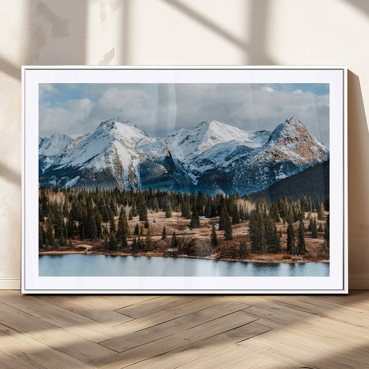 Framed canvas of snowy mountain peaks with pine forest and alpine lake, perfect for winter cabin or wilderness-inspired home decor.