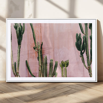 Framed canvas of tall green cacti against a soft pink wall, ideal for modern desert or colorful southwest-inspired home decor.