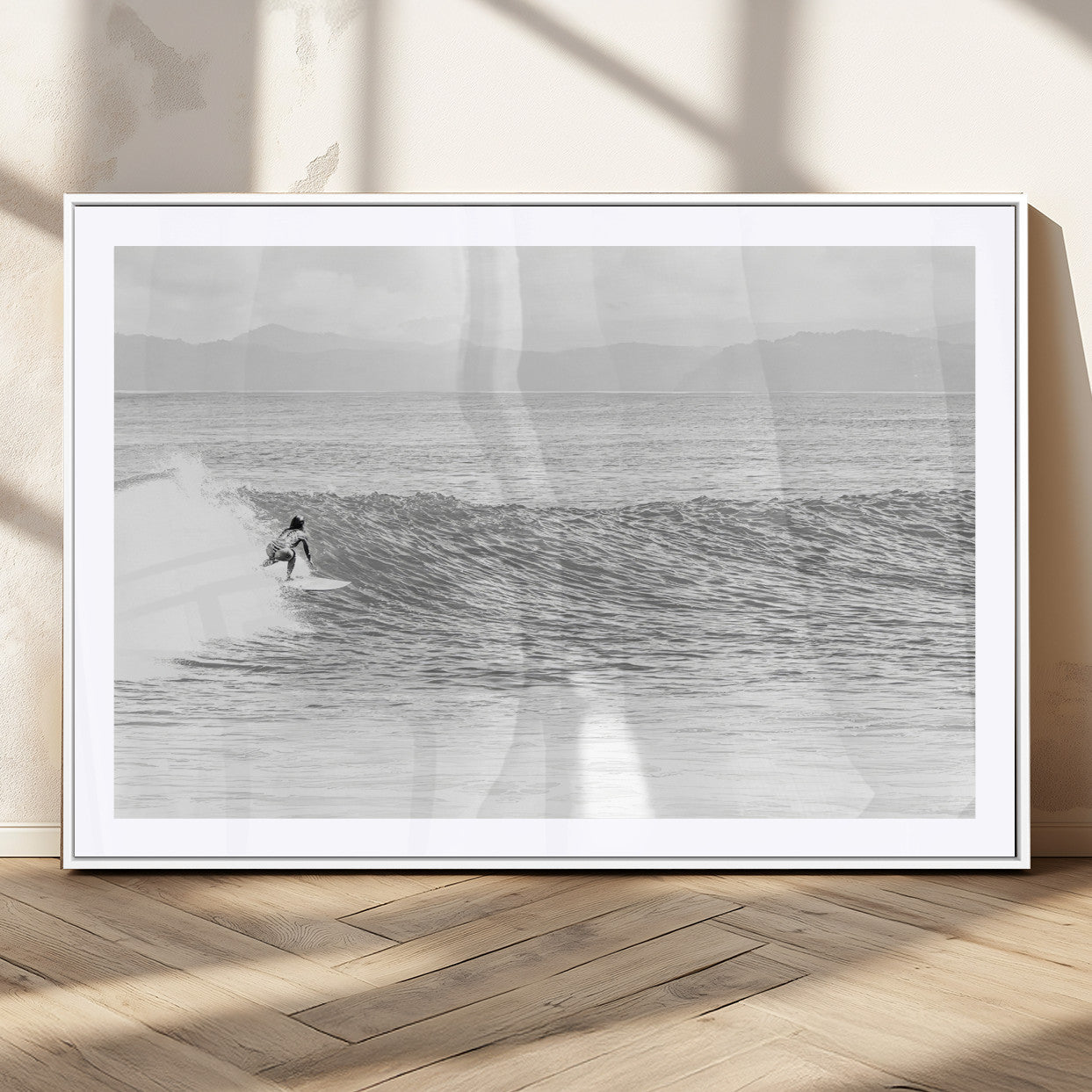 Monochrome photo of a surfer riding a wave with distant mountains, ideal for coastal motion or black and white surf-themed wall decor.