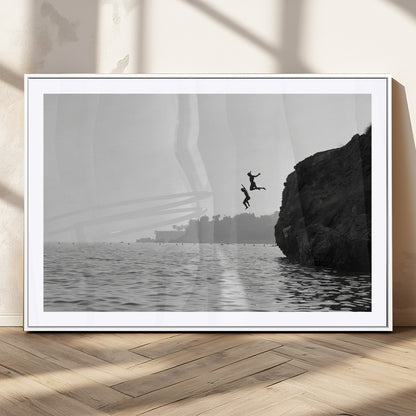 Black and white canvas of two figures cliff jumping into the sea, captured with moody tones, ideal for modern coastal or adventure-themed home decor.   2/2