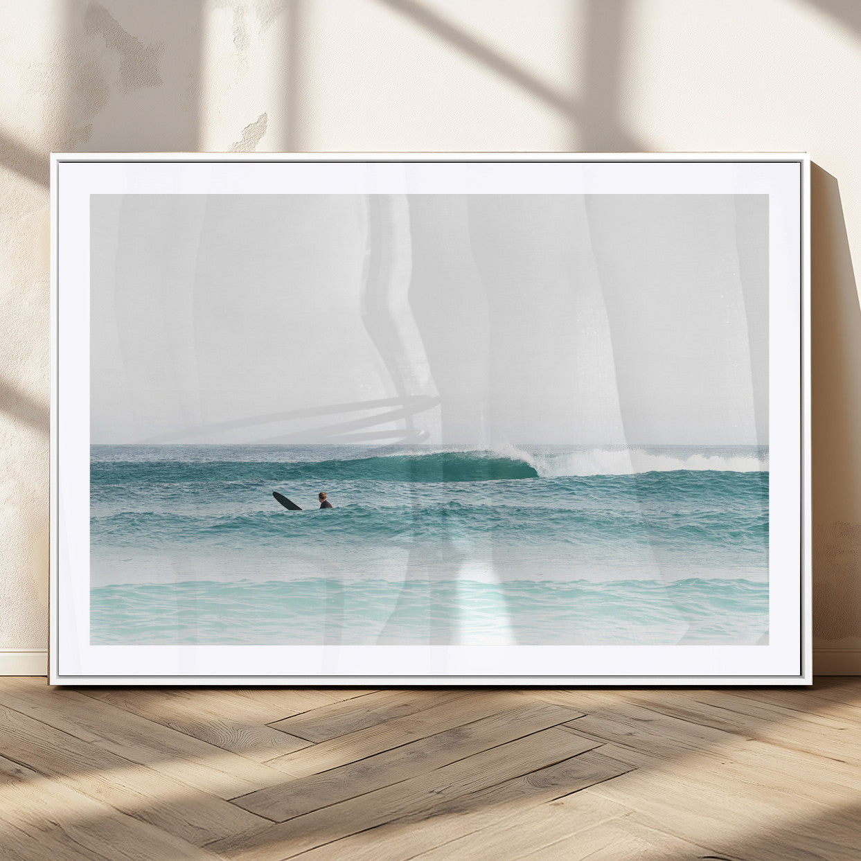 Minimalist photo of a lone surfer on calm aqua waves under bright sky, perfect for Scandinavian coastal or serene ocean-inspired home decor.