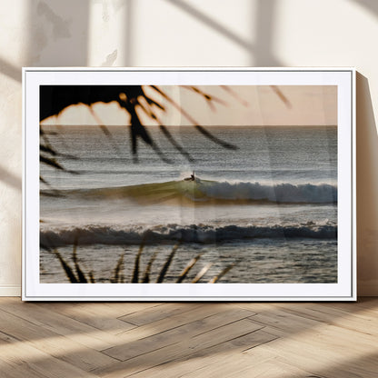 Photo of a surfer riding a golden hour wave at sunset, with tropical tones and dreamy light, perfect for tropical boho or coastal home decor.