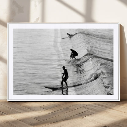 Black and white photo of surfers riding waves in a moody, high-contrast scene, ideal for modern coastal or surf-inspired home decor.