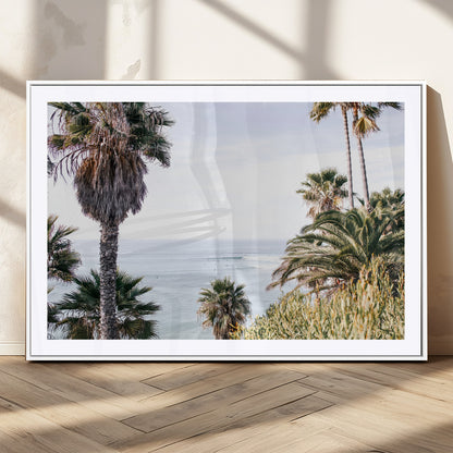 Scenic coastal view with tall palm trees overlooking a calm ocean, soft blue waves, and surfers in the distance, creating a peaceful tropical vibe.