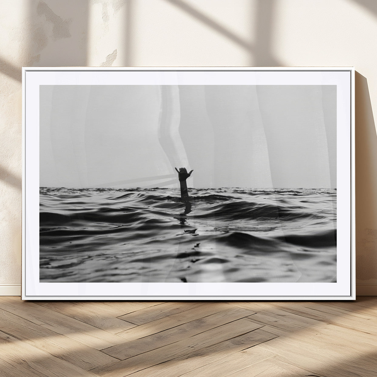Black and white ocean with a hand making a surfer sign among dark waves, creating a dramatic and minimalist seascape with bold contrast.