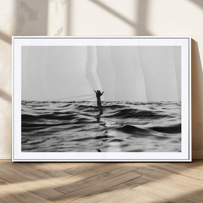Black and white ocean with a hand making a surfer sign among dark waves, creating a dramatic and minimalist seascape with bold contrast.
