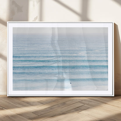 Minimalist ocean view with soft blue waves and a lone surfer, creating a serene and airy coastal aesthetic, perfect for tranquil home decor.
