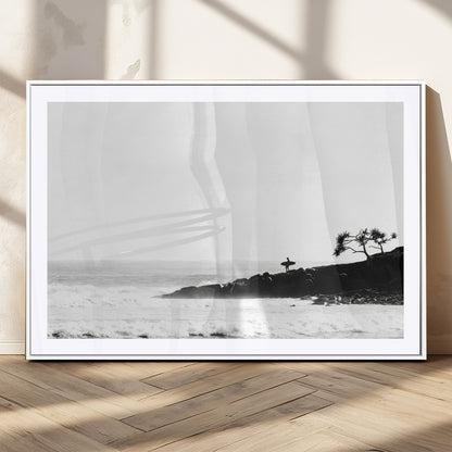 Black and white photo of a surfer standing on rocky cliffs, gazing at the waves, embodying the spirit of adventure and solitude.