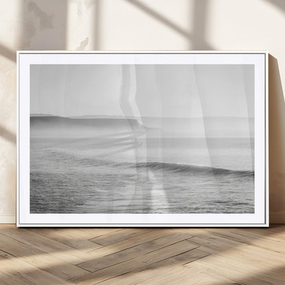 A black and white minimalist seascape featuring soft rolling waves and misty distant cliffs, creating a serene and timeless coastal atmosphere.