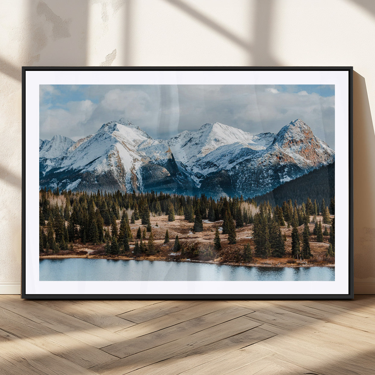 Framed canvas of snowy mountain peaks with pine forest and alpine lake, perfect for winter cabin or wilderness-inspired home decor.