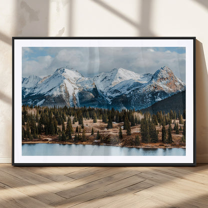 Framed canvas of snowy mountain peaks with pine forest and alpine lake, perfect for winter cabin or wilderness-inspired home decor.