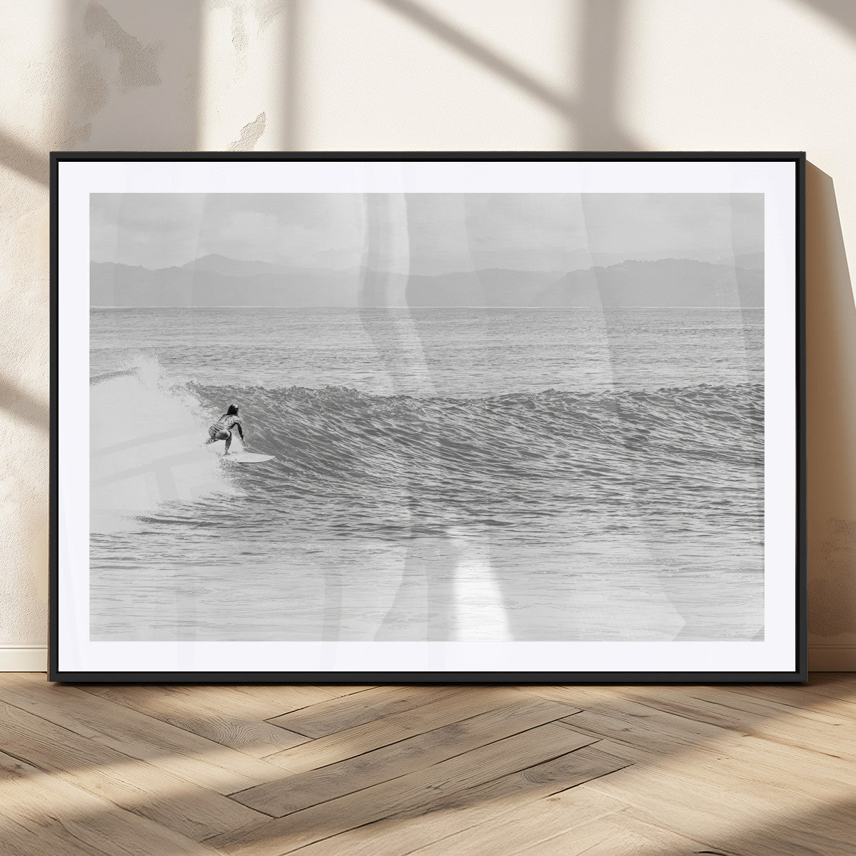 Monochrome photo of a surfer riding a wave with distant mountains, ideal for coastal motion or black and white surf-themed wall decor.