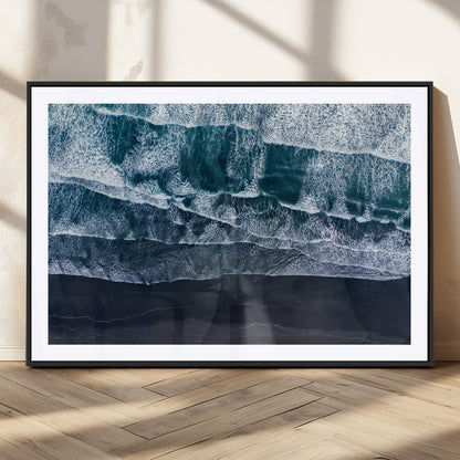 Canvas of aerial ocean waves crashing onto a black sand beach in moody tones, ideal for modern coastal or minimalist home decor.