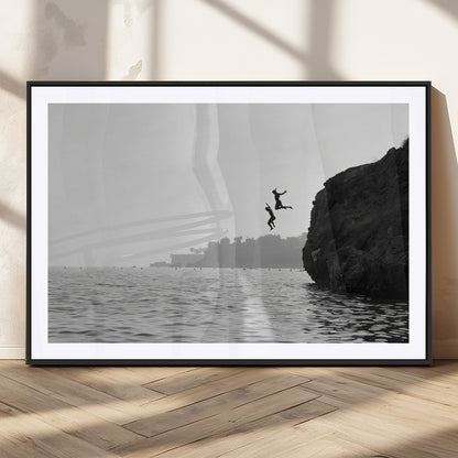 Black and white canvas of two figures cliff jumping into the sea, captured with moody tones, ideal for modern coastal or adventure-themed home decor.   2/2