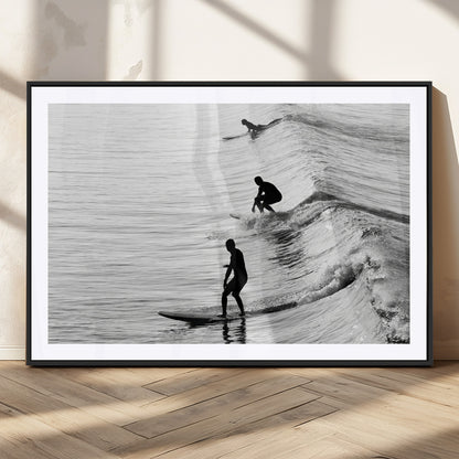 Black and white photo of surfers riding waves in a moody, high-contrast scene, ideal for modern coastal or surf-inspired home decor.