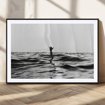 Black and white ocean with a hand making a surfer sign among dark waves, creating a dramatic and minimalist seascape with bold contrast.