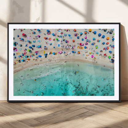 Aerial view of a vibrant beach filled with colorful umbrellas and people enjoying the turquoise ocean, capturing a lively summer vacation scene.