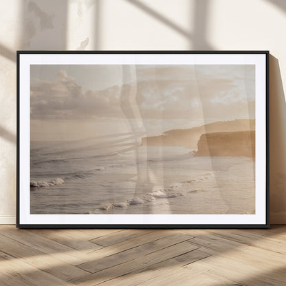 Golden hour seascape with misty cliffs and gentle waves rolling towards the shore, capturing a tranquil and warm coastal atmosphere.