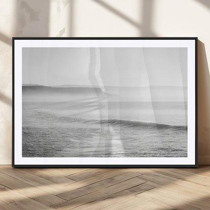 A black and white minimalist seascape featuring soft rolling waves and misty distant cliffs, creating a serene and timeless coastal atmosphere.