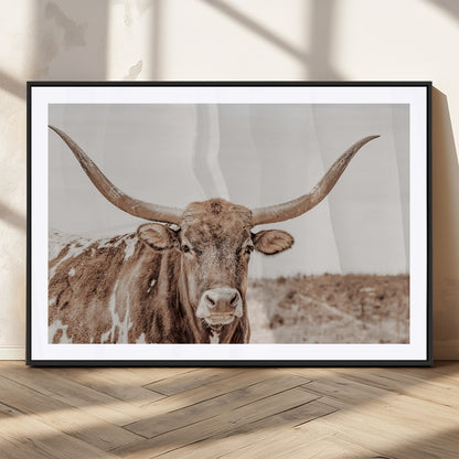 A longhorn cow in soft beige desert tones, standing calmly in open land, perfect for neutral western or rustic farmhouse interiors.