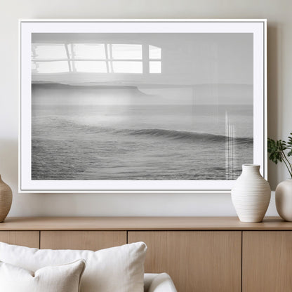 A black and white minimalist seascape featuring soft rolling waves and misty distant cliffs, creating a serene and timeless coastal atmosphere.