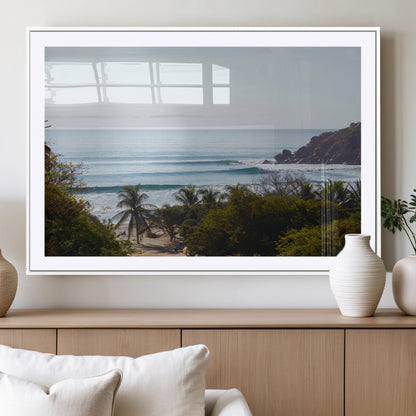 View of calm ocean waves with palm trees and a tropical coastline, ideal for coastal boho or beach-themed wall decor.