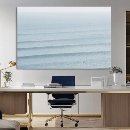 Framed canvas of repeating ocean waves with a distant solo surfer, ideal for minimalist ocean or calm coastal wall decor.